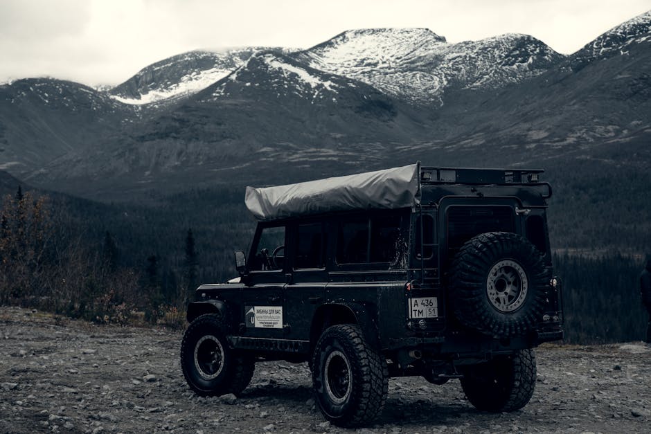 Explore rugged terrain in Murmansk Oblast, Russia, with an off-road vehicle against majestic mountain backdrops.